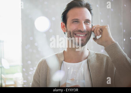 Smiling man drinking water and talking on cell phone Stock Photo