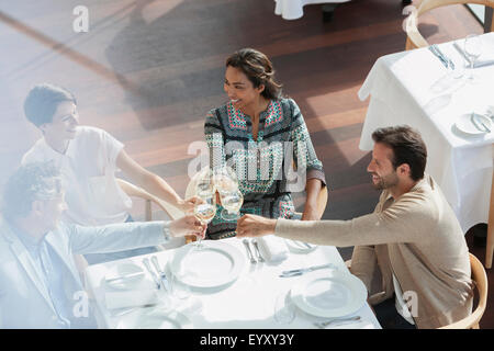 Friends toasting wine glasses at restaurant table Stock Photo