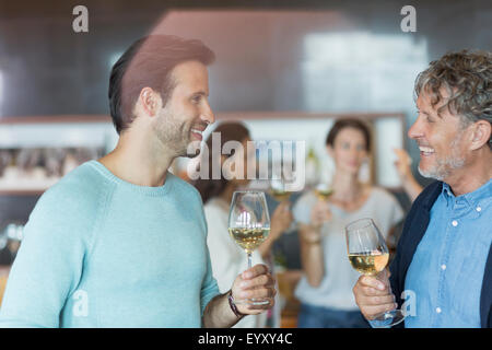 Friends wine tasting and talking in winery tasting room Stock Photo