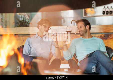 Men wine tasting at fireplace in winery tasting room Stock Photo