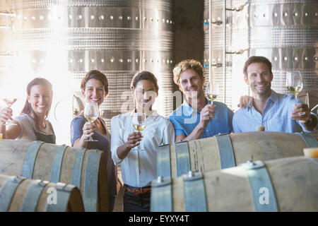 Portrait smiling winery employees barrel tasting in cellar Stock Photo
