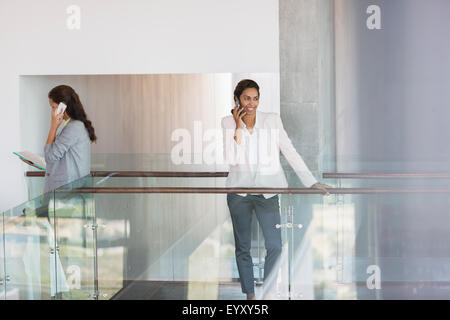 Businesswoman talking on cell phone in office Stock Photo