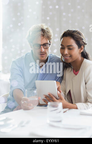 Couple using digital tablet at restaurant table Stock Photo