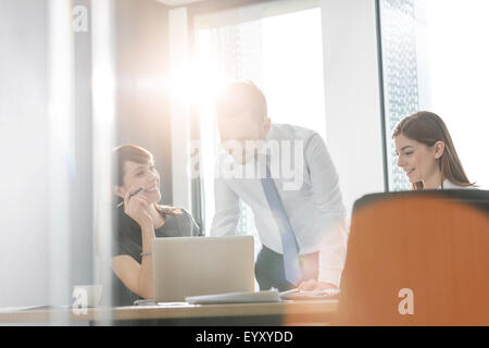 Business people working at laptop in sunny conference room meeting Stock Photo