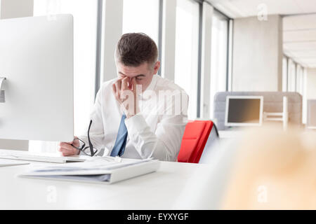 Tired businessman rubbing eyes at computer in office Stock Photo