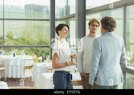 Friends talking and drinking wine in winery dining room Stock Photo