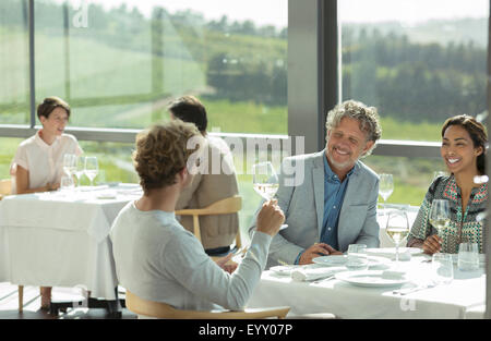 Friends drinking wine and talking in winery dining room Stock Photo
