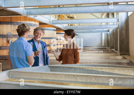 Friends barrel tasting wine in winery cellar Stock Photo