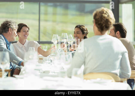 Friends toasting wine glasses in sunny restaurant Stock Photo