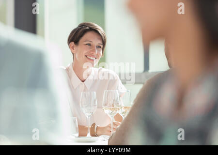 Smiling woman drinking white wine in sunny restaurant Stock Photo