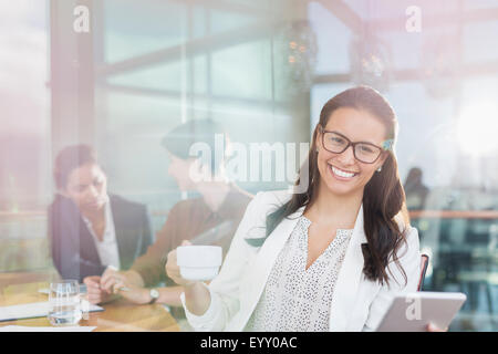 Portrait confident businesswoman with digital tablet and coffee in office Stock Photo