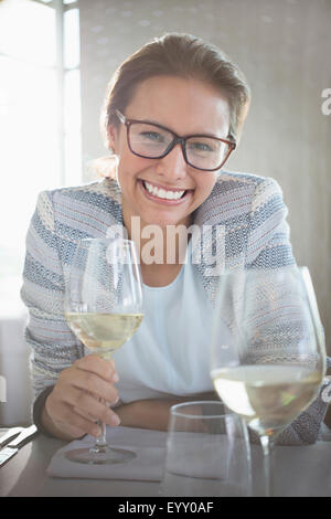 Portrait confident woman with eyeglasses drinking white wine Stock Photo