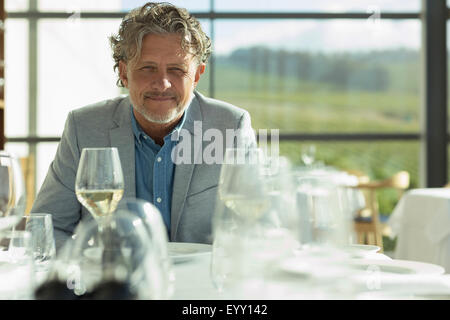 Portrait confident man with white wine at sunny restaurant table Stock Photo