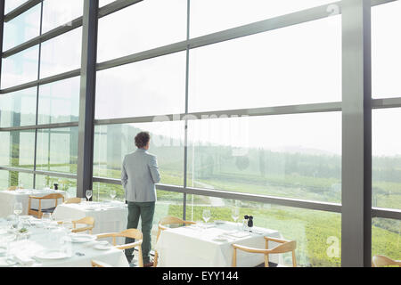 Man standing at sunny window in winery dining room Stock Photo