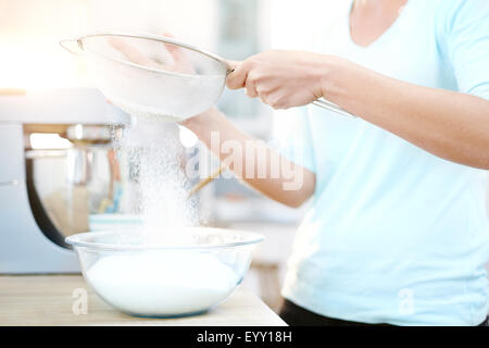 Woman sifting flour and baking in kitchen Stock Photo
