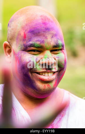 Smiling man covered in pigment powder gesturing peace sign, Stock Photo