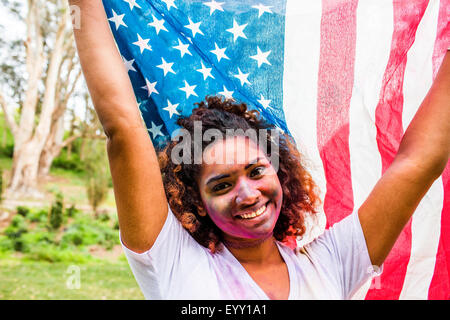 Mixed race woman covered in pigment powder holding American flag Stock Photo