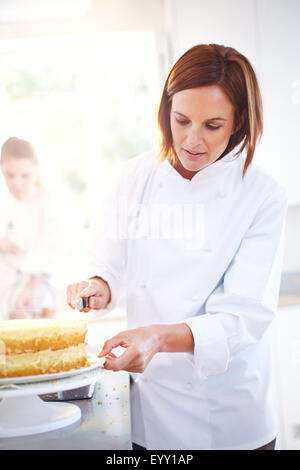 Chef frosting cake in kitchen Stock Photo