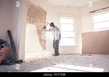 Hispanic construction worker demolishing wall Stock Photo