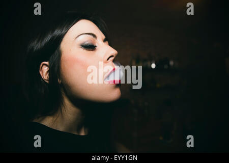 Caucasian woman smoking in nightclub Stock Photo