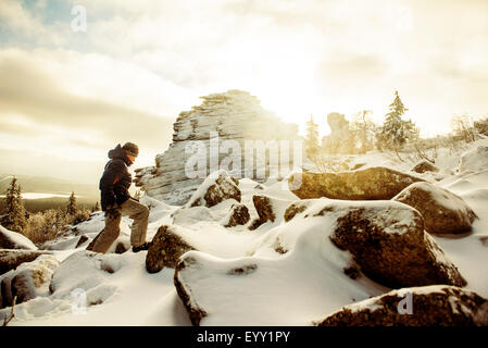 Caucasian hiker climbing snowy rock formations Stock Photo