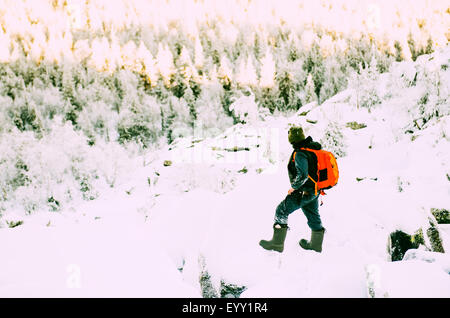 Caucasian hiker climbing snowy rock formations Stock Photo
