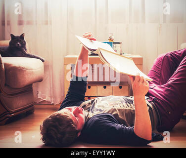 Caucasian man reading on living room floor Stock Photo