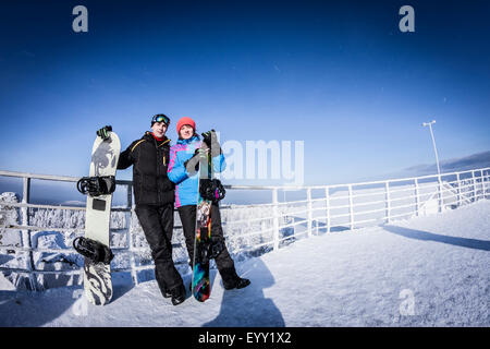 Caucasian snowboarders standing on mountaintop Stock Photo