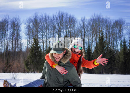 Caucasian couple playing in snowy field Stock Photo