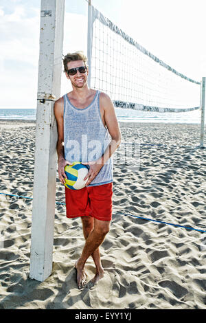 Caucasian man holding volleyball on beach Stock Photo