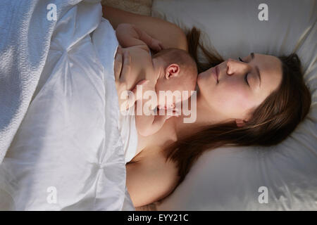 Mother sleeping with newborn baby on bed Stock Photo