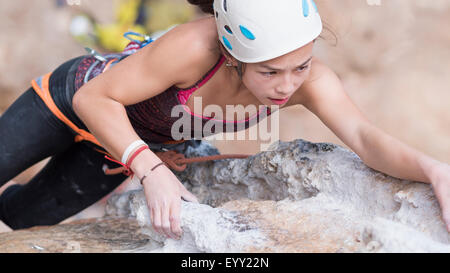 Mixed race girl climbing rock wall Stock Photo