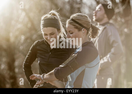 Caucasian runners checking fitness watch in forest Stock Photo