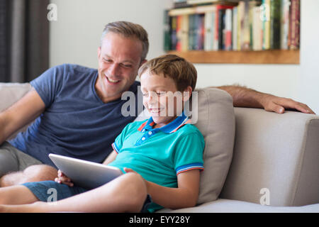 Caucasian father and son using digital tablet on sofa Stock Photo