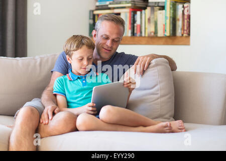 Caucasian father and son using digital tablet on sofa Stock Photo