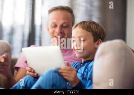 Caucasian father and son using digital tablet on sofa Stock Photo