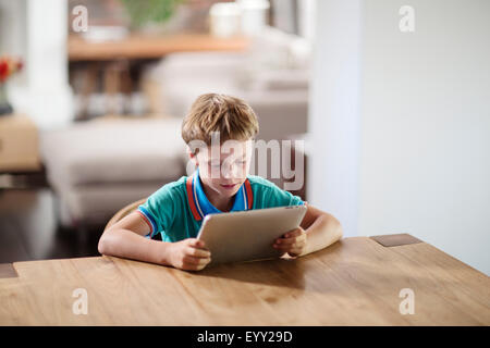Caucasian boy using digital tablet at table Stock Photo