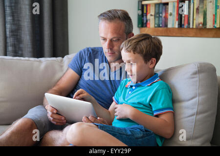 Caucasian father and son using digital tablet on sofa Stock Photo