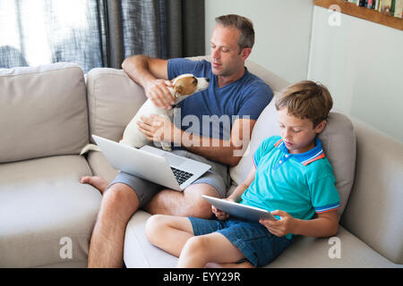 Caucasian father and son using technology on sofa Stock Photo