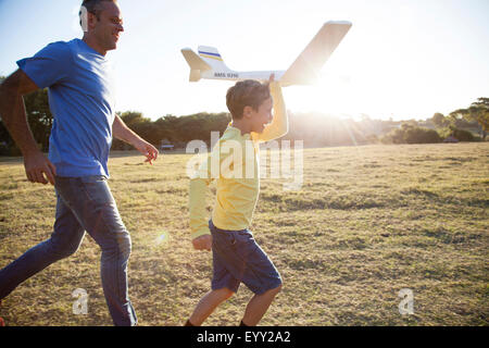 Caucasian father and son flying model airplane in field Stock Photo