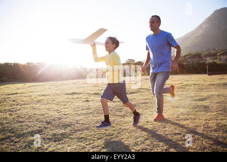 Caucasian father and son flying model airplane in field Stock Photo