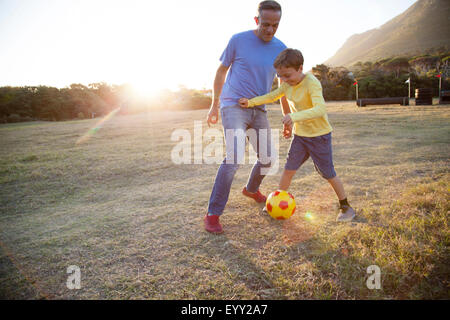 Caucasian father and son playing soccer in field Stock Photo