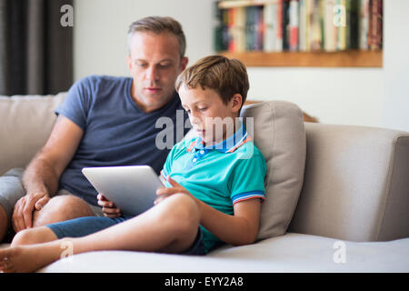 Caucasian father and son using digital tablet on sofa Stock Photo