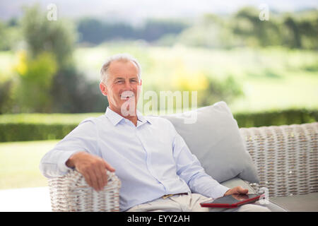 Caucasian man using digital tablet on sofa outdoors Stock Photo