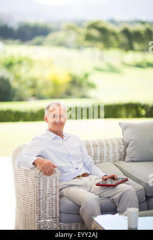 Caucasian man using digital tablet on sofa outdoors Stock Photo