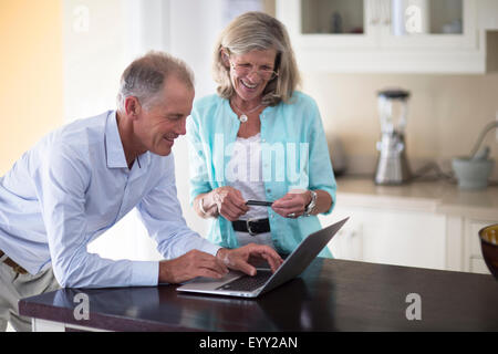 Caucasian couple using laptop on kitchen counter Stock Photo
