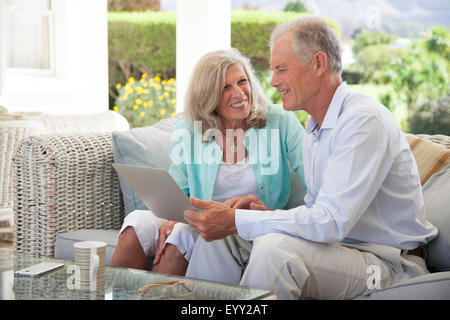 Caucasian couple using laptop on sofa outdoors Stock Photo