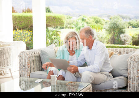 Caucasian couple using digital tablet on sofa outdoors Stock Photo
