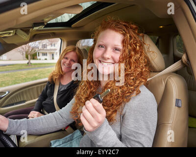 Caucasian teenage girl showing key with mother in car Stock Photo