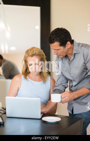 Business people drinking coffee and using laptop at desk Stock Photo